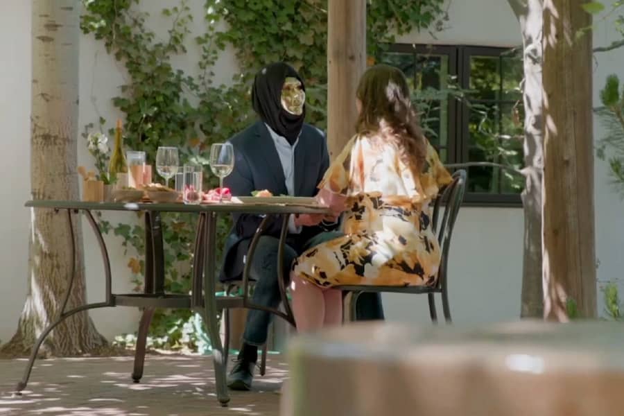 gold face mask guy having a patio lunch with a woman