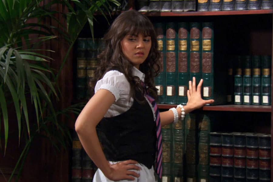 Penelope leans against a bookcase