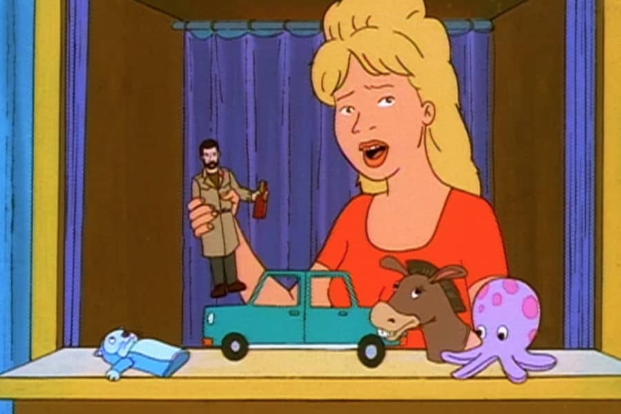 Luanne and her puppets, she holds a doll of a man holding an alcohol bottle by a model car