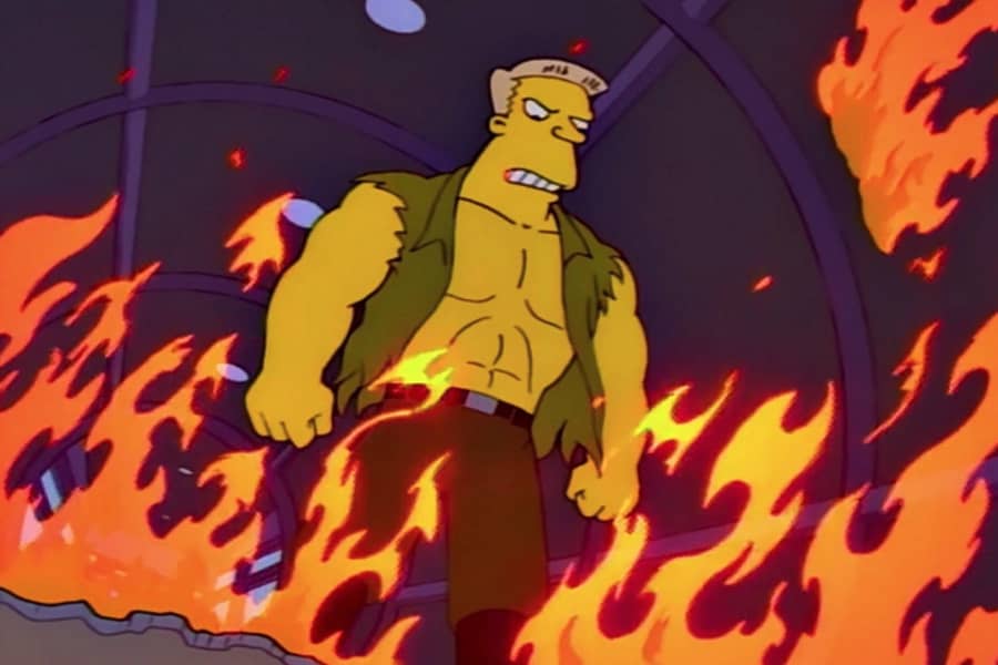 McBain in a torn shirt looks at the ground from a cargo plane on fire
