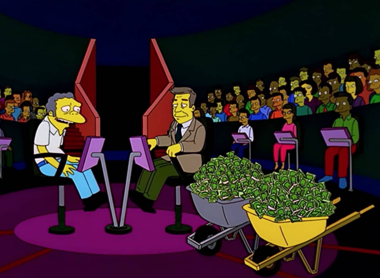 Moe Szyslak sits across from Virgil Sinclair on the set of a game show, two wheelbarrows of cash sit nearby