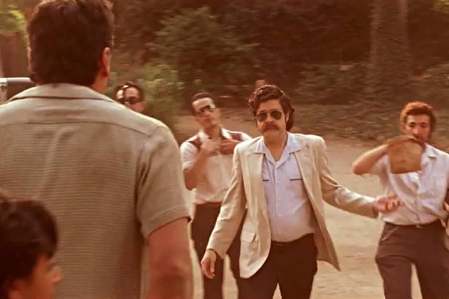 Escobar approaches a man with a paper bag