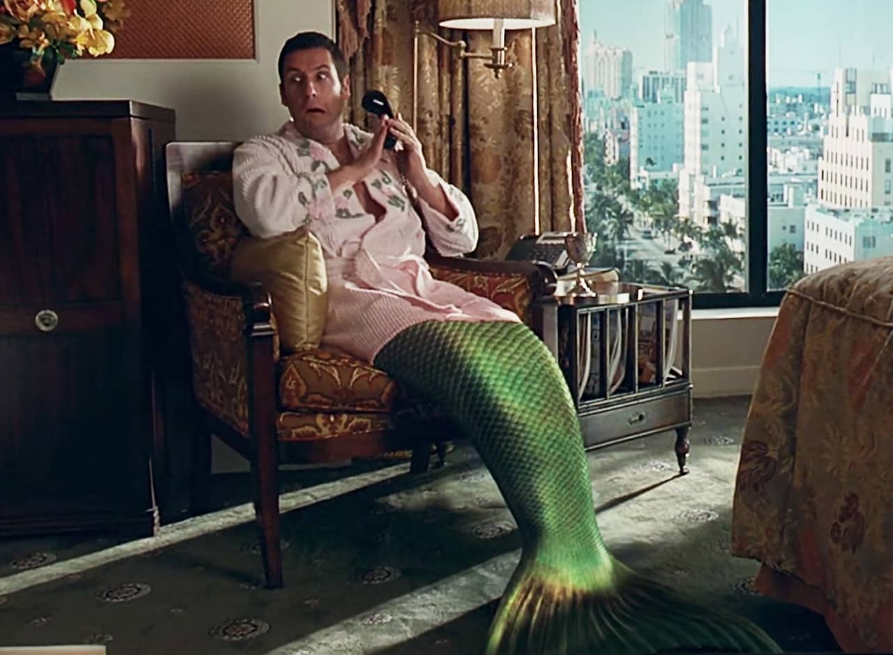 George Simmons, with a fish‘s tail, sits in a hotel bathrobe on the phone
