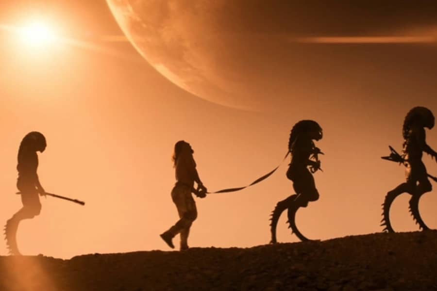 Momoa is a prisoner, walking through the desert led by tall aliens