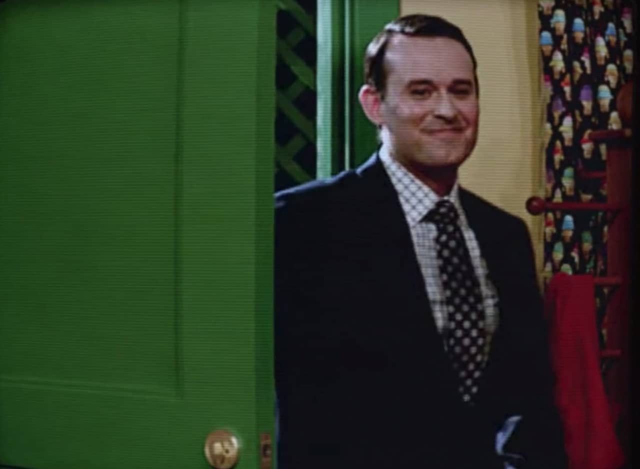 Mr. Parker, a jovial man in a suit, entering a house through the green front door