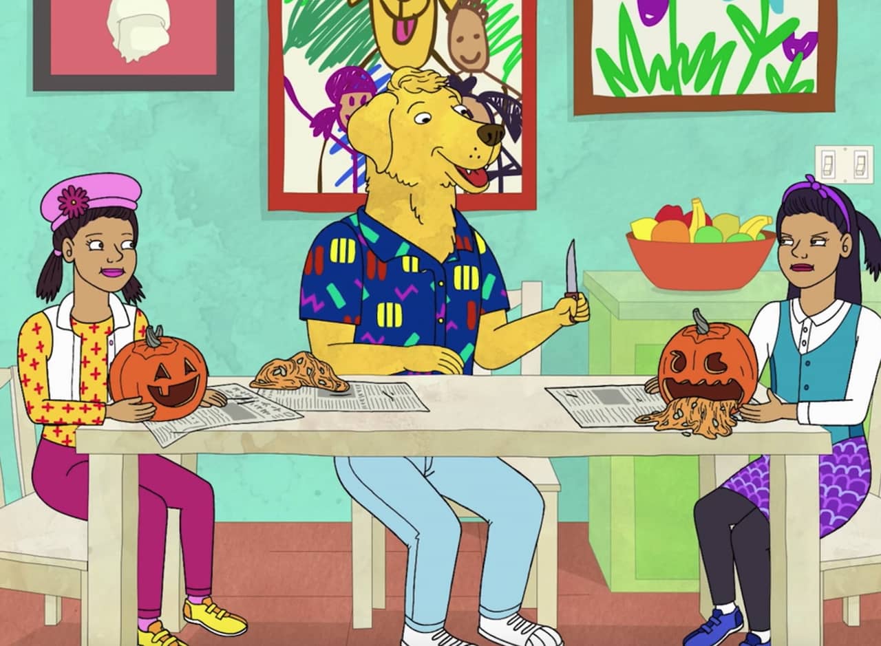 Mr. Peanutbutter in a 90s shirt carves pumpkins with two girls at a table