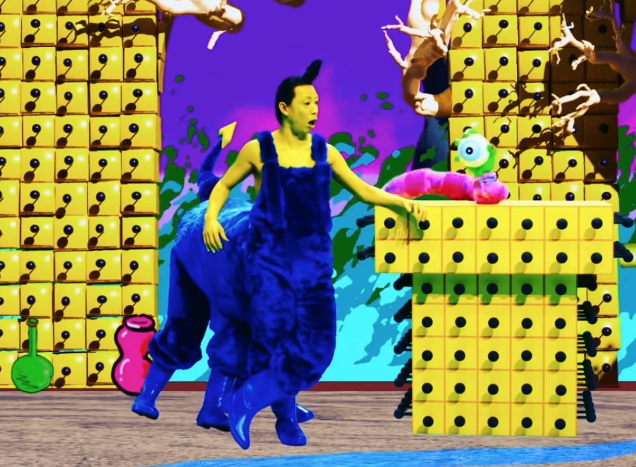 a CGI, brightly colored tv set with a host who has painted yellow skin and wearing furry blue centaur overalls