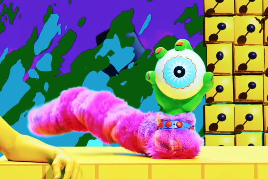 a green hand holds a giant eyeball and has a pink furry tail