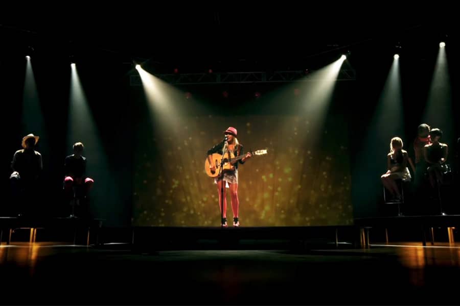 blonde teen singing and playing guitar