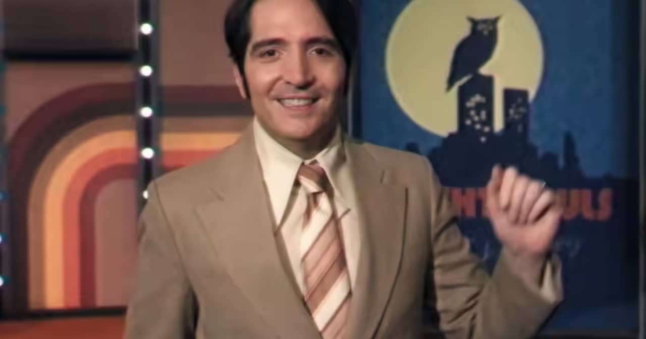 Jack Delroy in a tan suit, giving his opening monologue