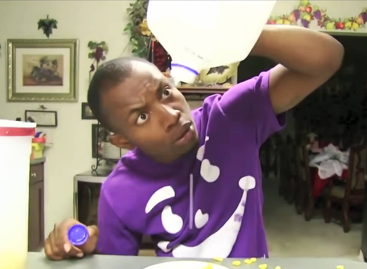 man holding an empty milk jug upside down over a cereal bowl