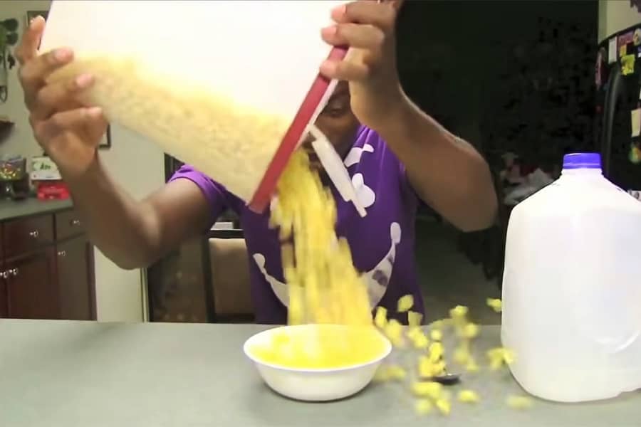 man pouring cereal into a bowl and it’s overflowing all over the table
