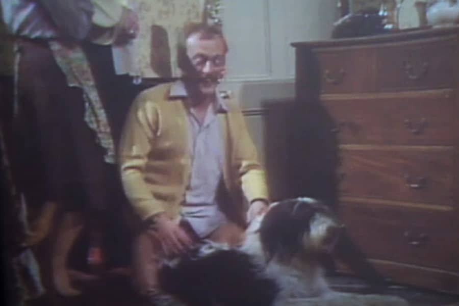 pantsless man sitting on the floor next to the dog