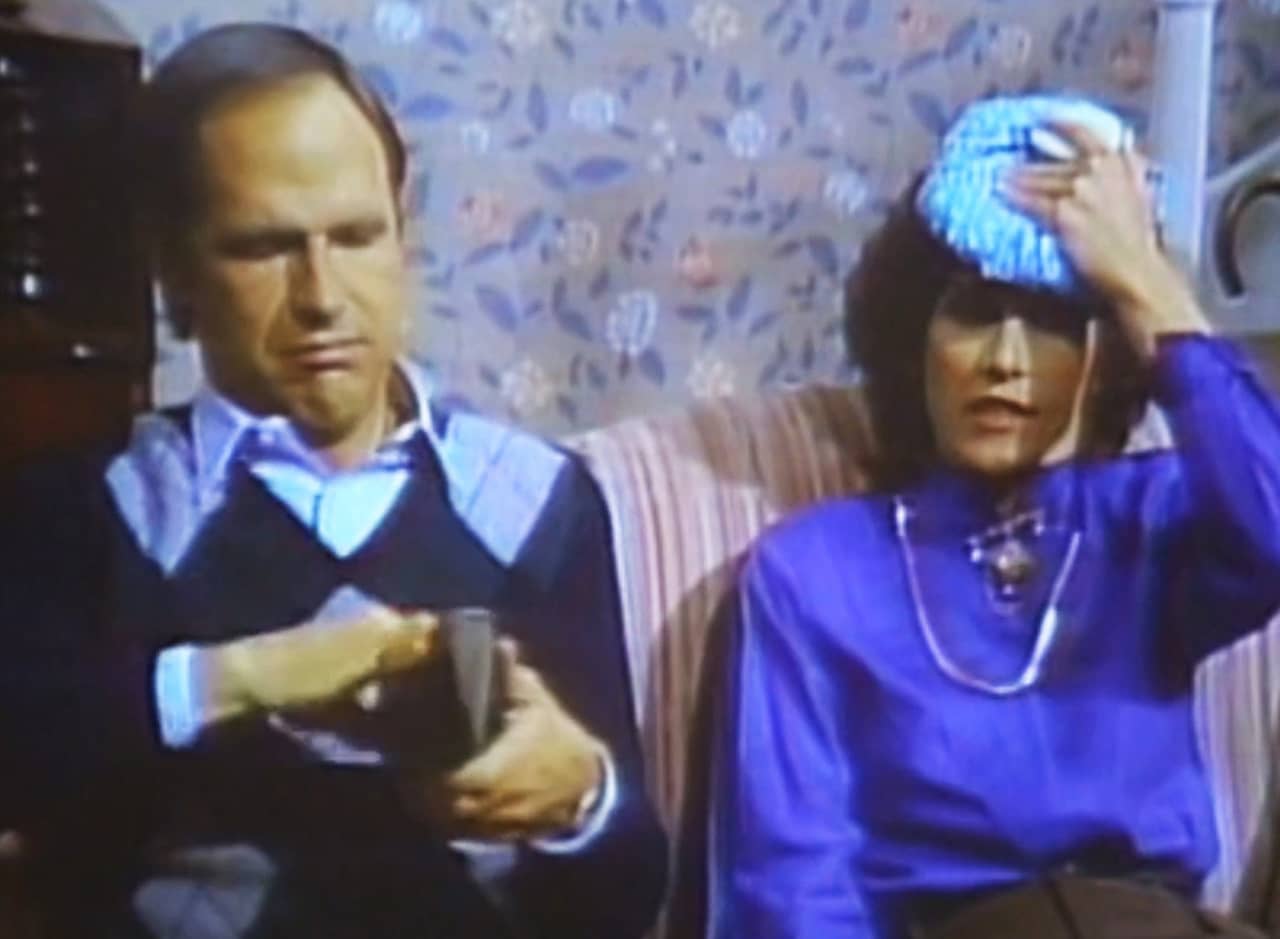 man and woman on the couch, the woman is holding a compress to her head