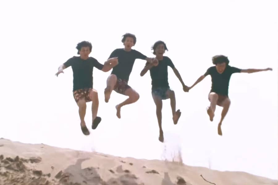 the Rutles jumping all together in a sand dune