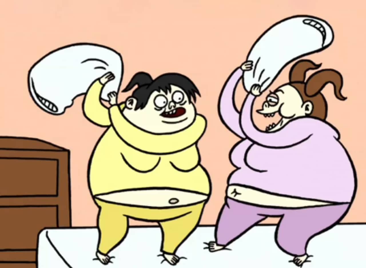 two women wearing pajama sets and having a pillow fight on a bed