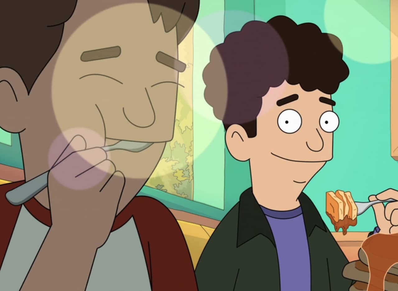 curly-haired boy eating pancakes smiling at another boy