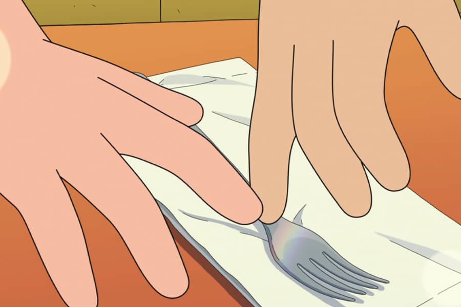 two hands touch as they reach for a fork
