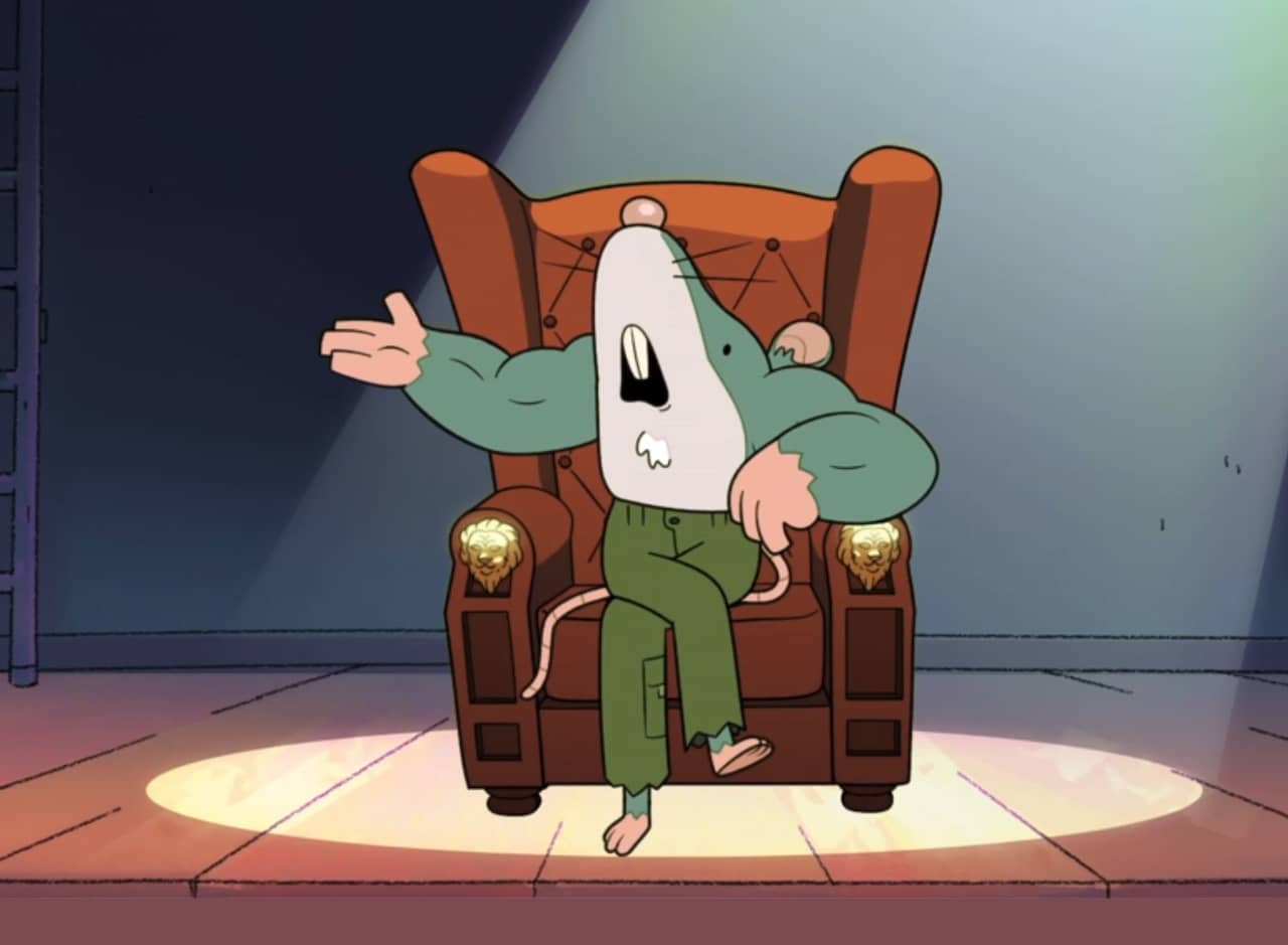 Muscle Mouse sitting on a stage in an armchair lit by a spotlight