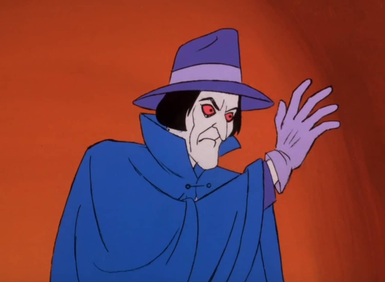 the phantom, a man with white face and red eyes wearing a cape and fedora