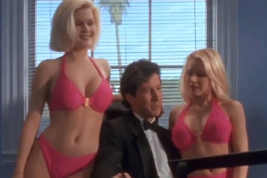 human Duckman sitting at a desk with two women in pink bikinis