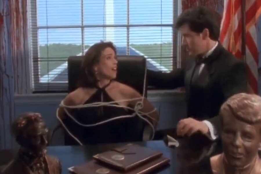 woman is tied up to a chair as human Duckman tries to free her, out the window is the Washington Monument