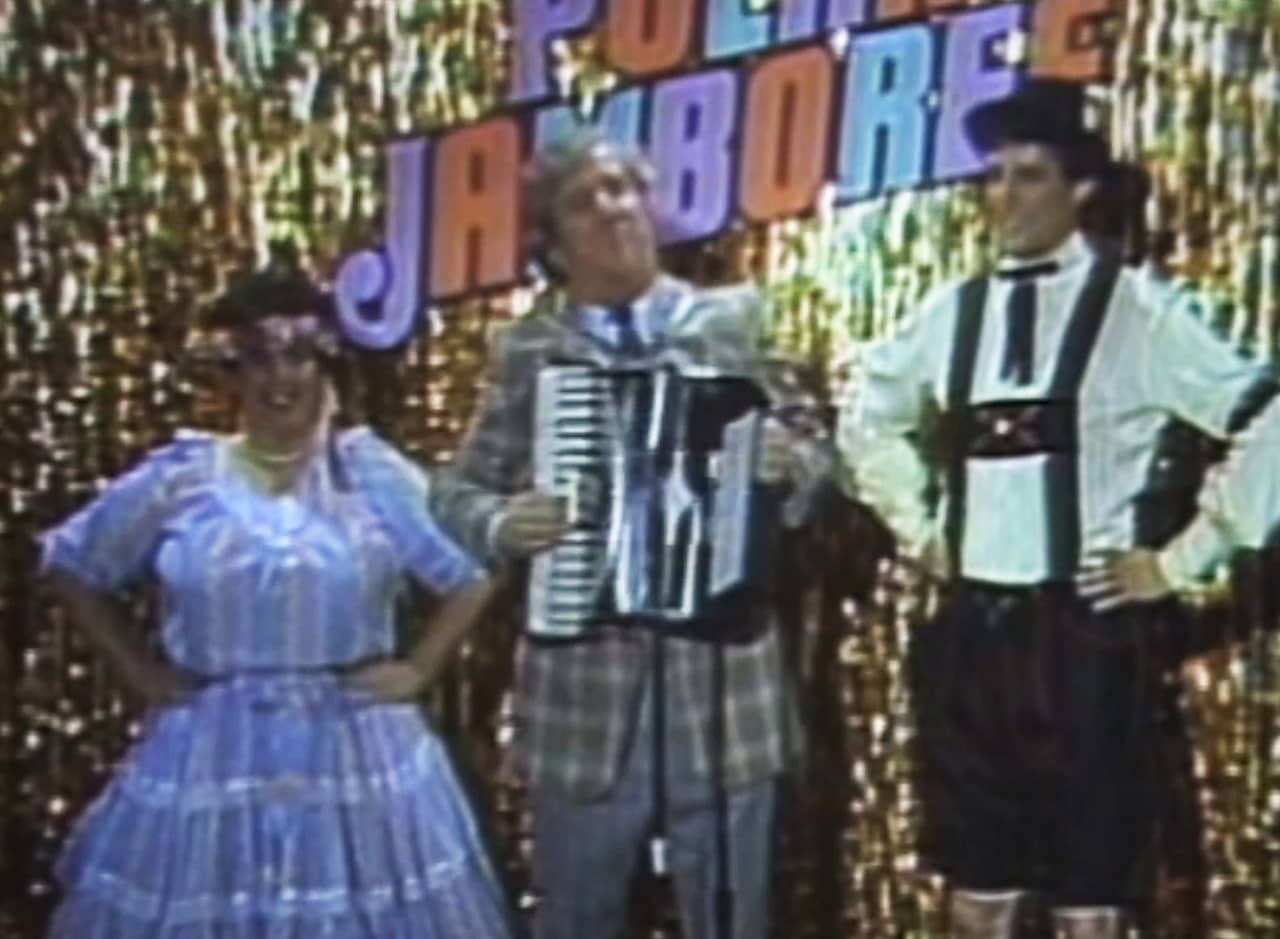 man with an accordion with a man in lederhosen and a woman in traditional dress