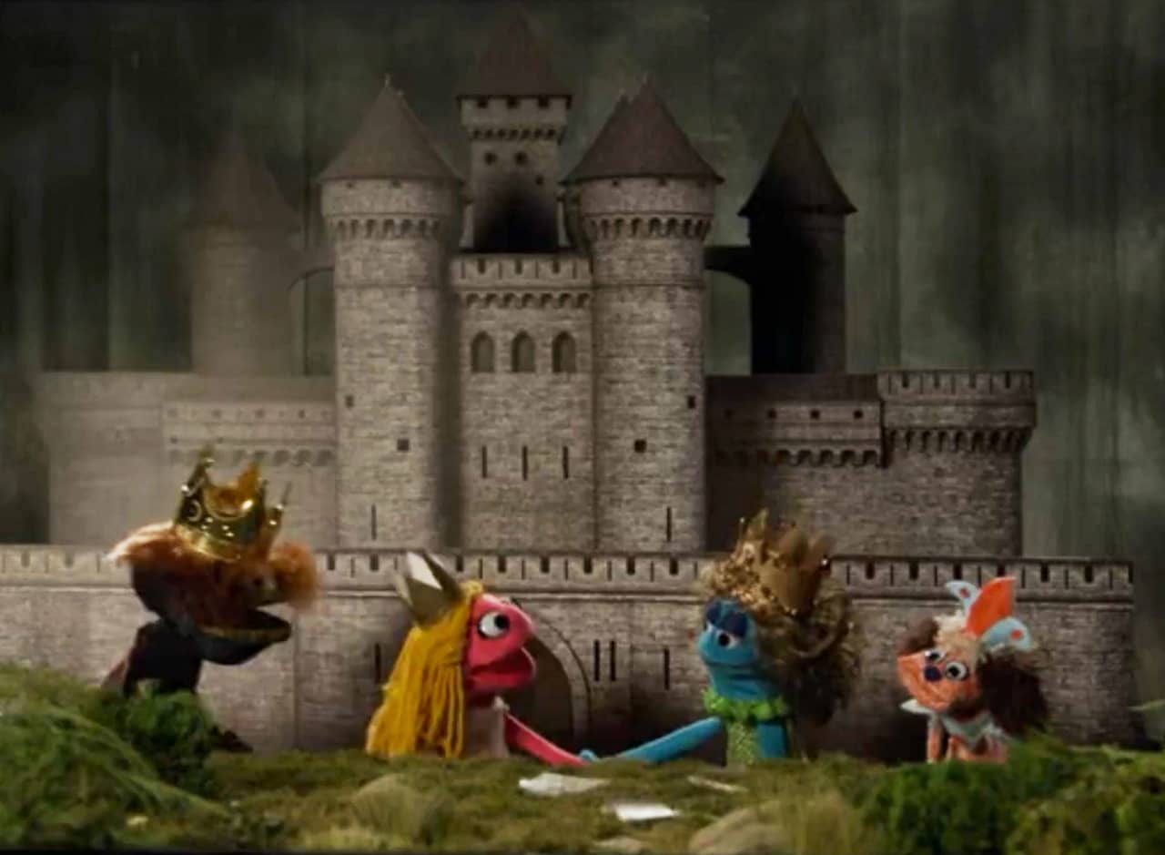 a group of four royal puppets in front of a castle