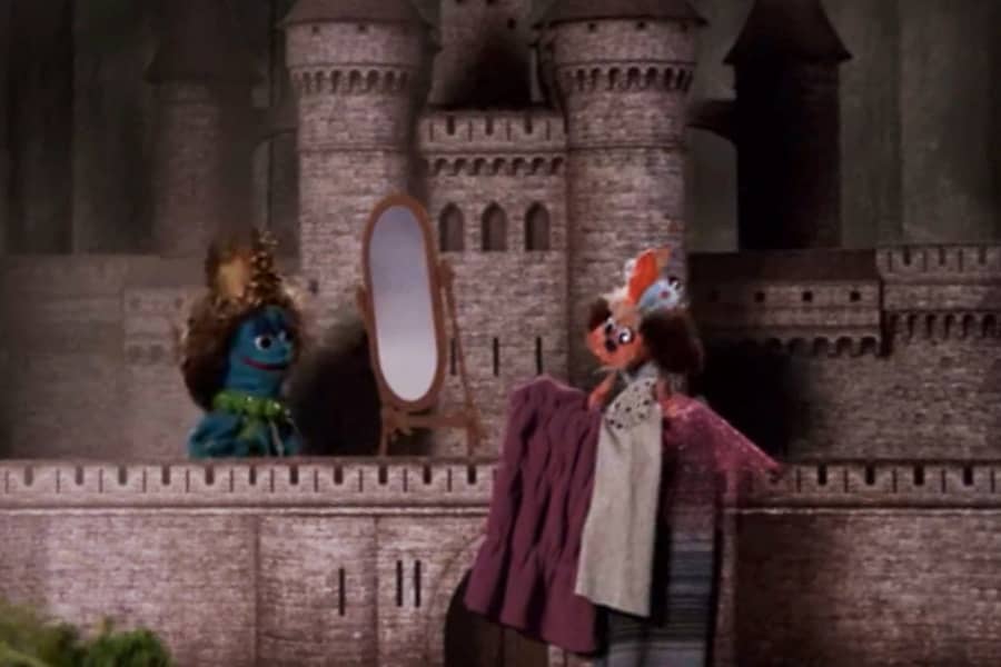two puppets try on clothes in front of a mirror
