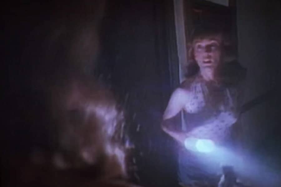 a red-haired woman holds a flashlight, frightened to see the blonde woman