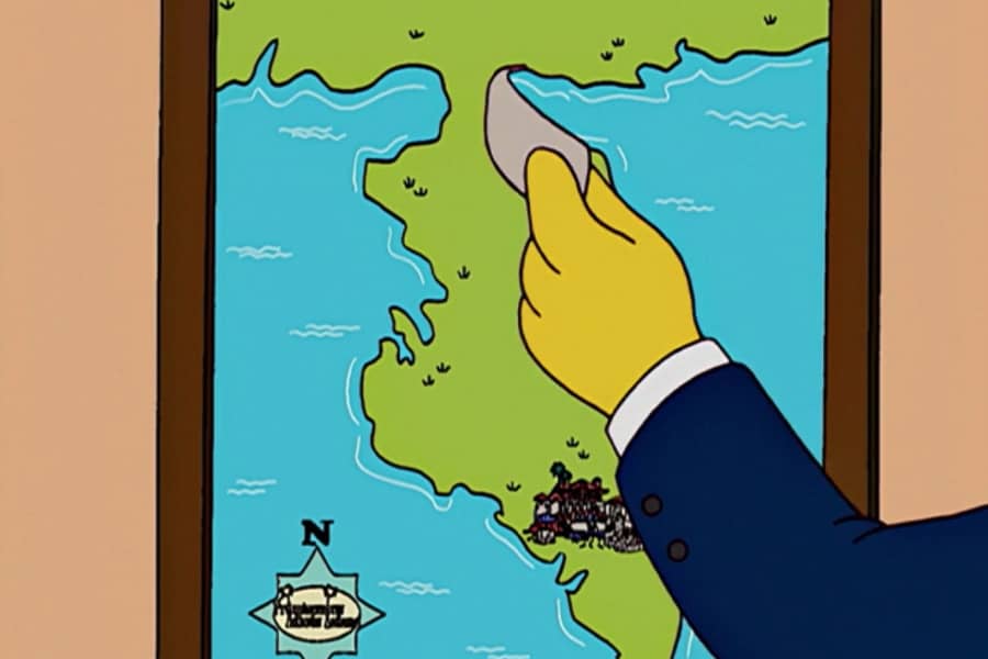 a hand removes a strip of paper from a map of the island revealing it’s a peninsula