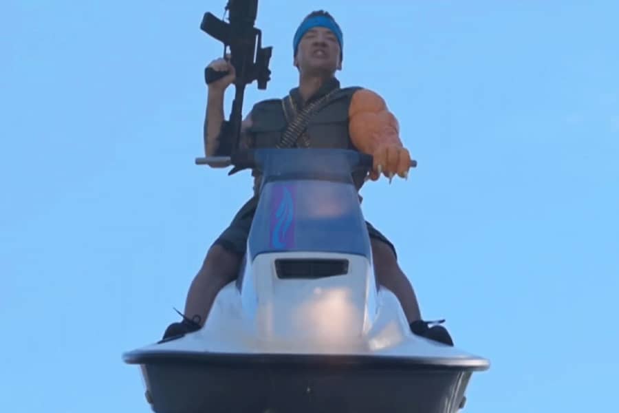 David Faustino with one huge arm, holding a gun on a jetski