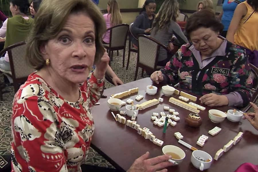 Lucille speaks to the camera at the mahjong table