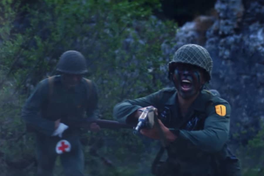 a soldier yells and runs holding a gun, a medic runs behind him