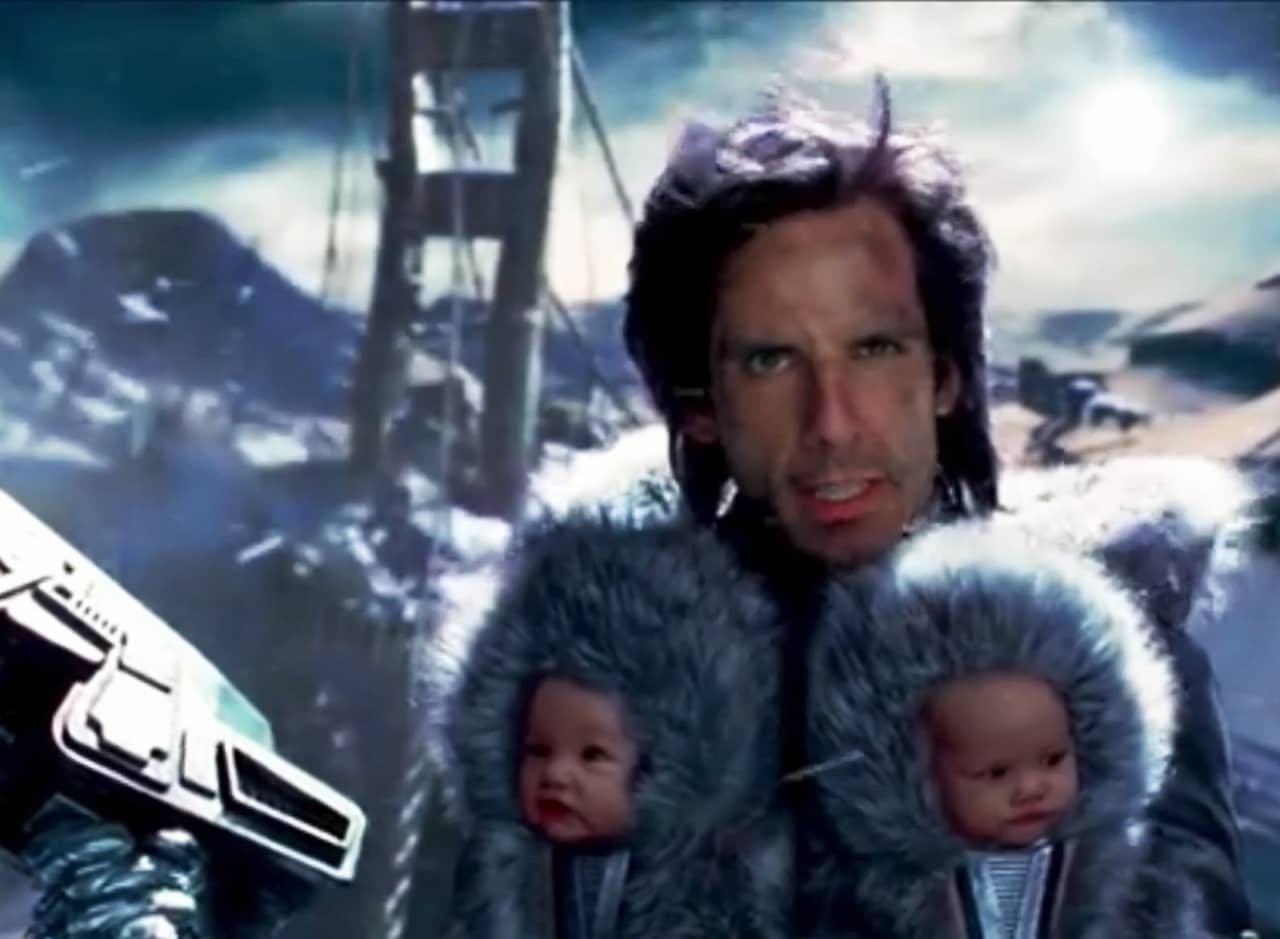 Speedman in front of a frozen landscape with two babies in furry hoods strapped to his chest