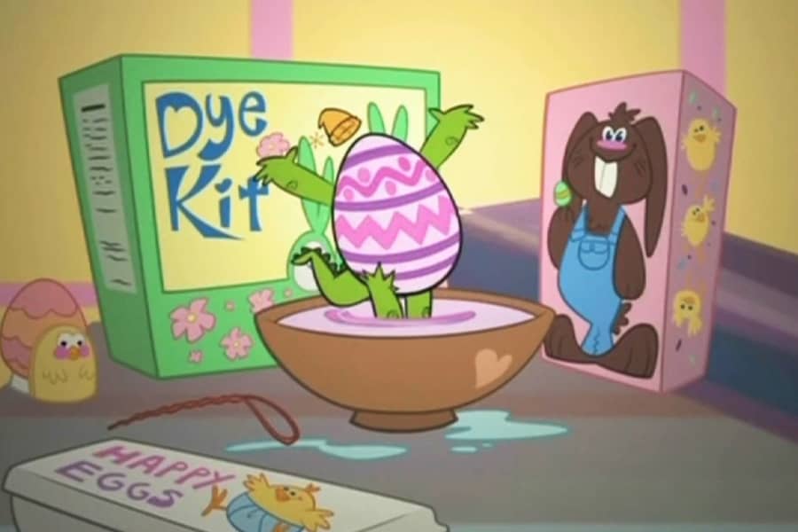Crocco the egg standing up, now Easter ecorated, in a bowl of egg dye