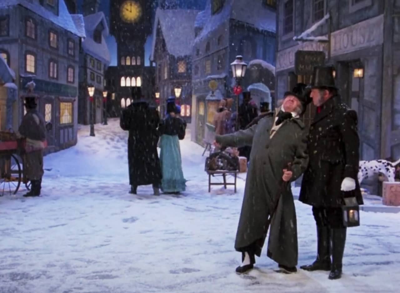 Scrooge stands in a snowy city street