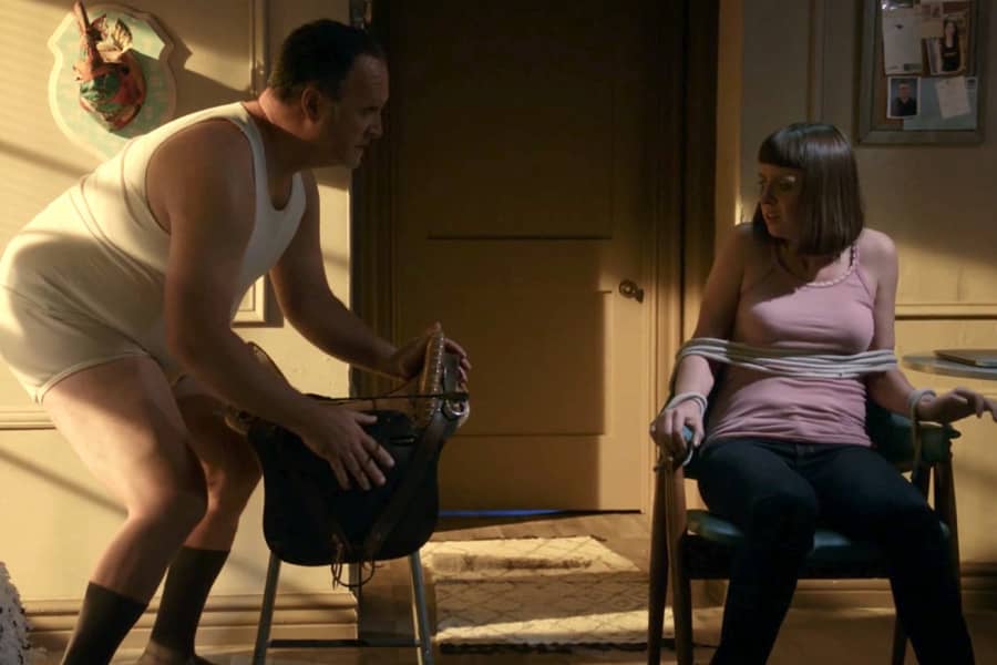 a creepy man in his underwear talks with a young woman tied to a chair