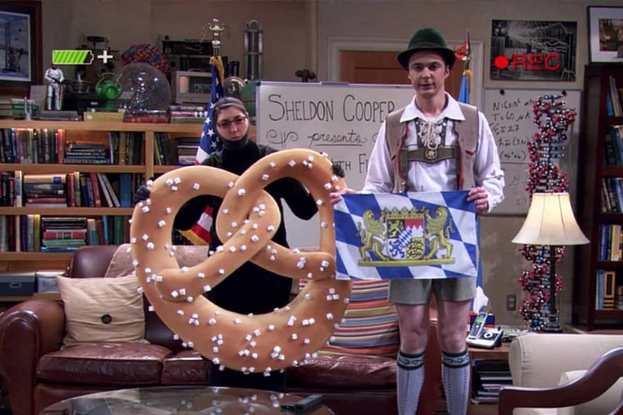 Cooper dressed in lederhosen and Amy Farrah Fowler dressed as a giant pretzel with the flag of Bavaria