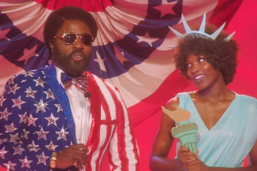 Sherman wearing an American flag suit standing with a woman dressed as the statue of liberty