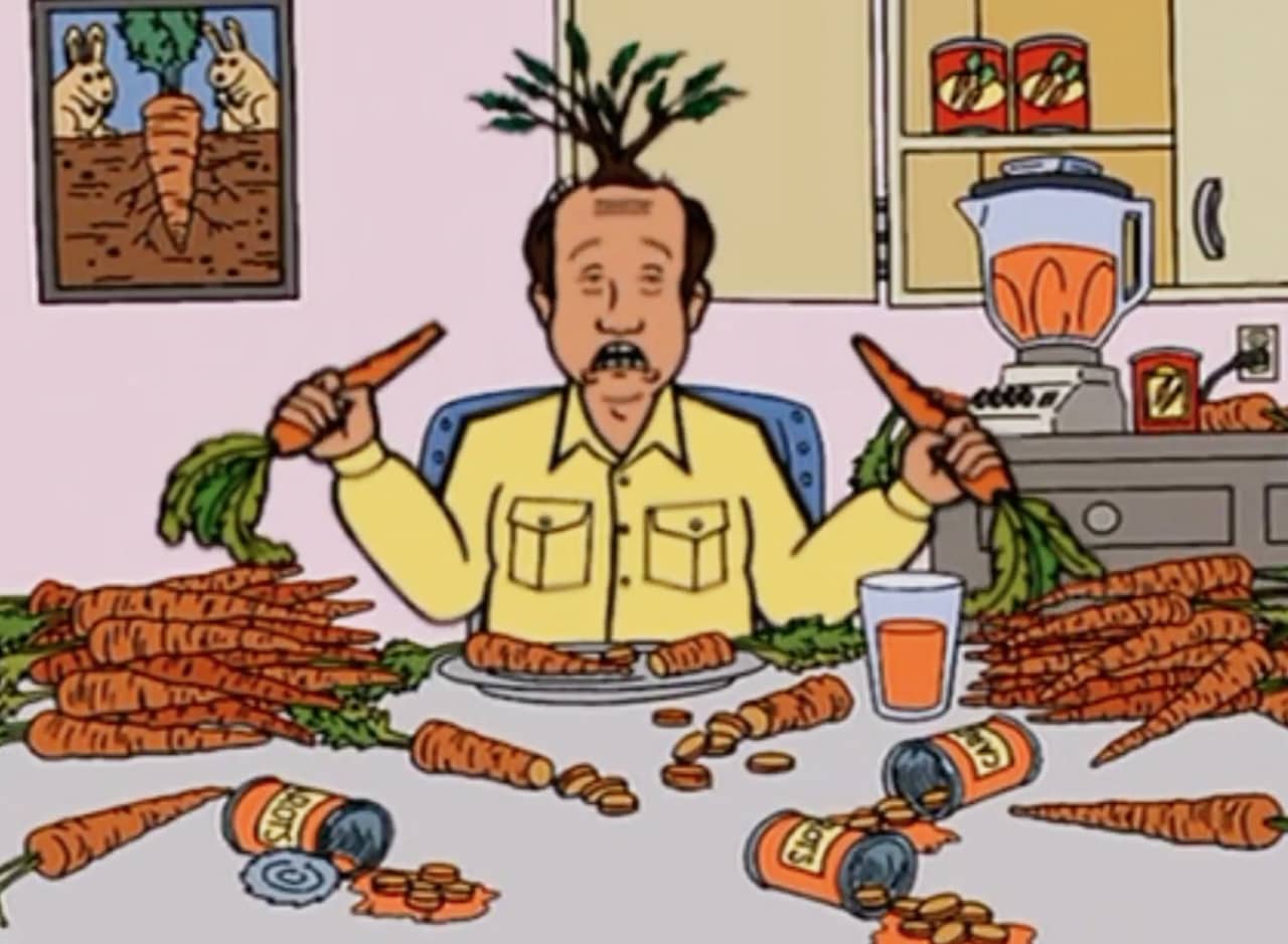 a man double fists carrots at a table covered in carrots and a tree grows out the top of his head