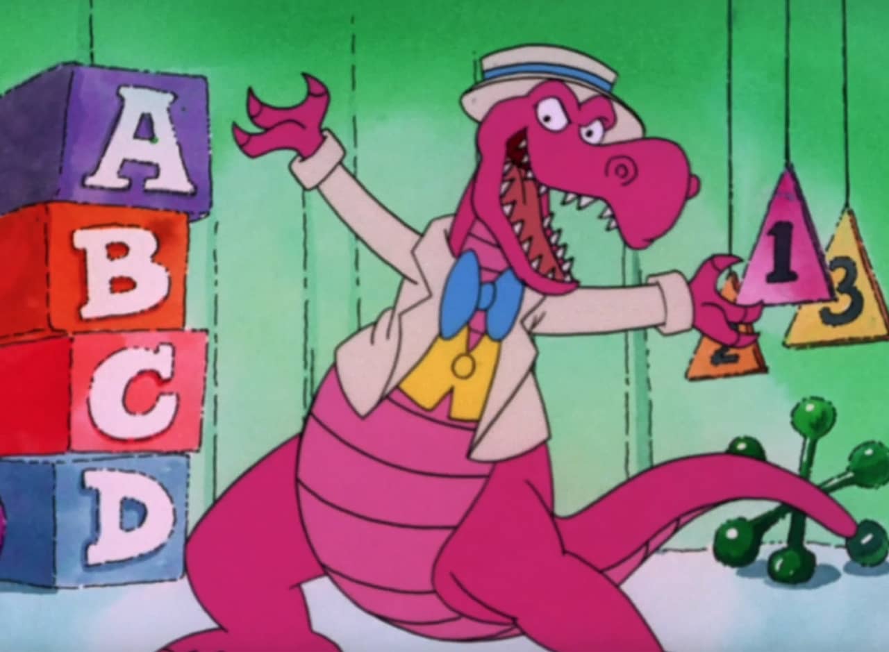 Sidney, a pink dinosaur wearing tuxedo top and boater hat, dancing on a set decorated with big alphabet blocks