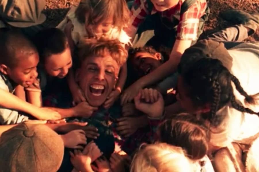 Jack laughs as he is surrounded by lots of kids