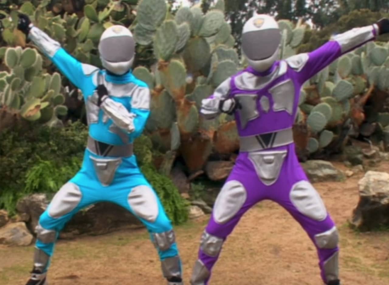 two boys in futuristic blue and purple jumpsuits, wearing helmets that obscure their faces