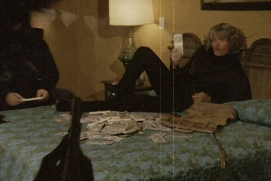 a man lies on a hotel bed next to a pile of cash