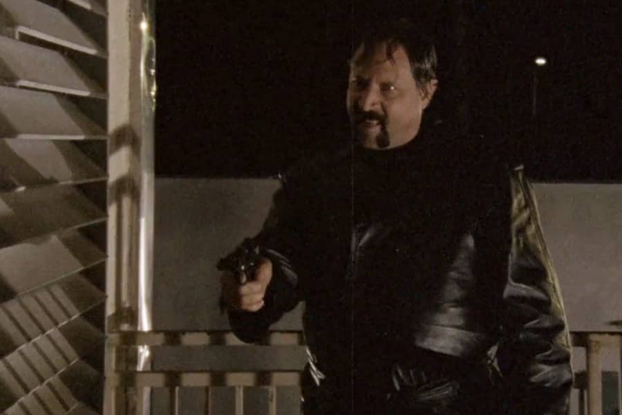 mustached man holds a gun