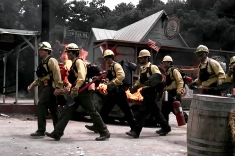 firemen walk through a town on fire