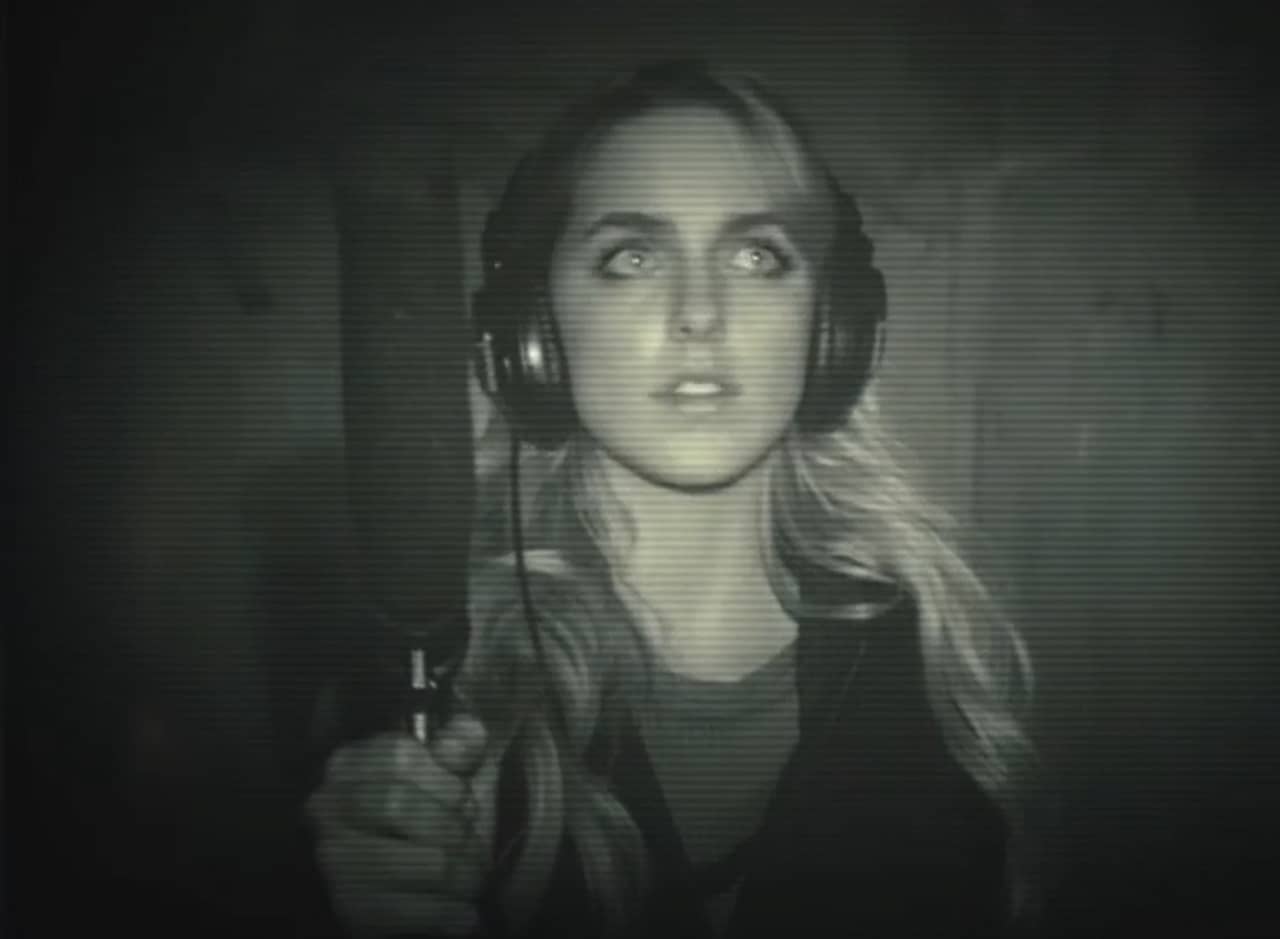 night vision shot of Lisa, a young blonde woman, wearing headphones and carrying a boom microphone