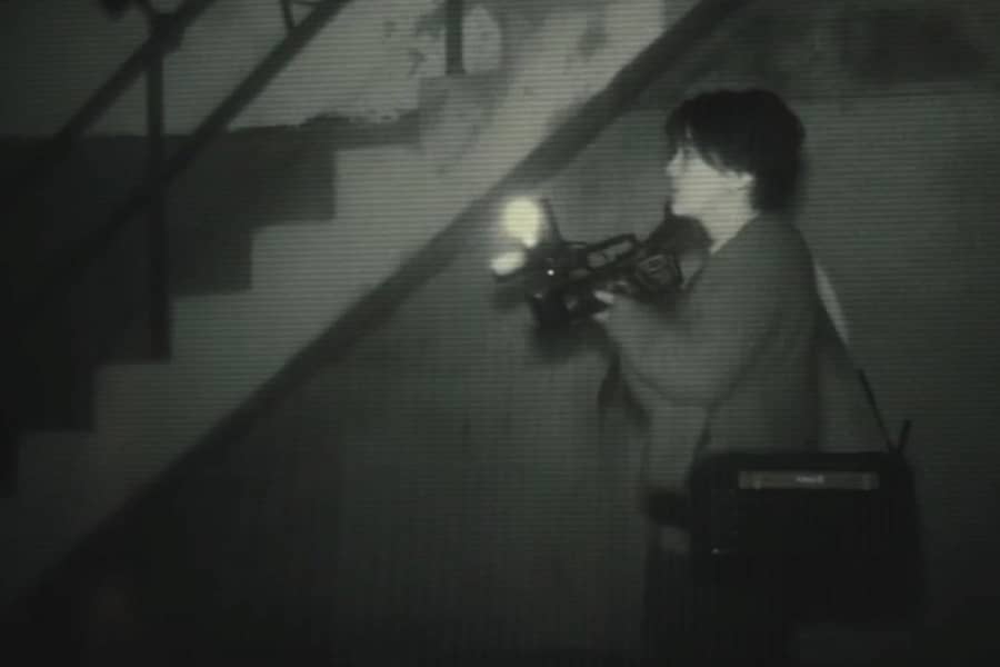 Rob holding a video camera near a concrete flight of stairs