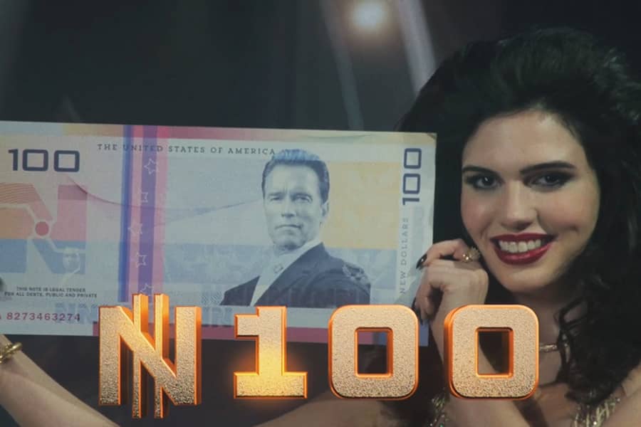 hostess holds up a large 100 new dollar bill with Arnold Schwarzenegger’s face on it
